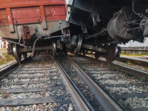 A black train goes off the rails and bumps into the red one next to it