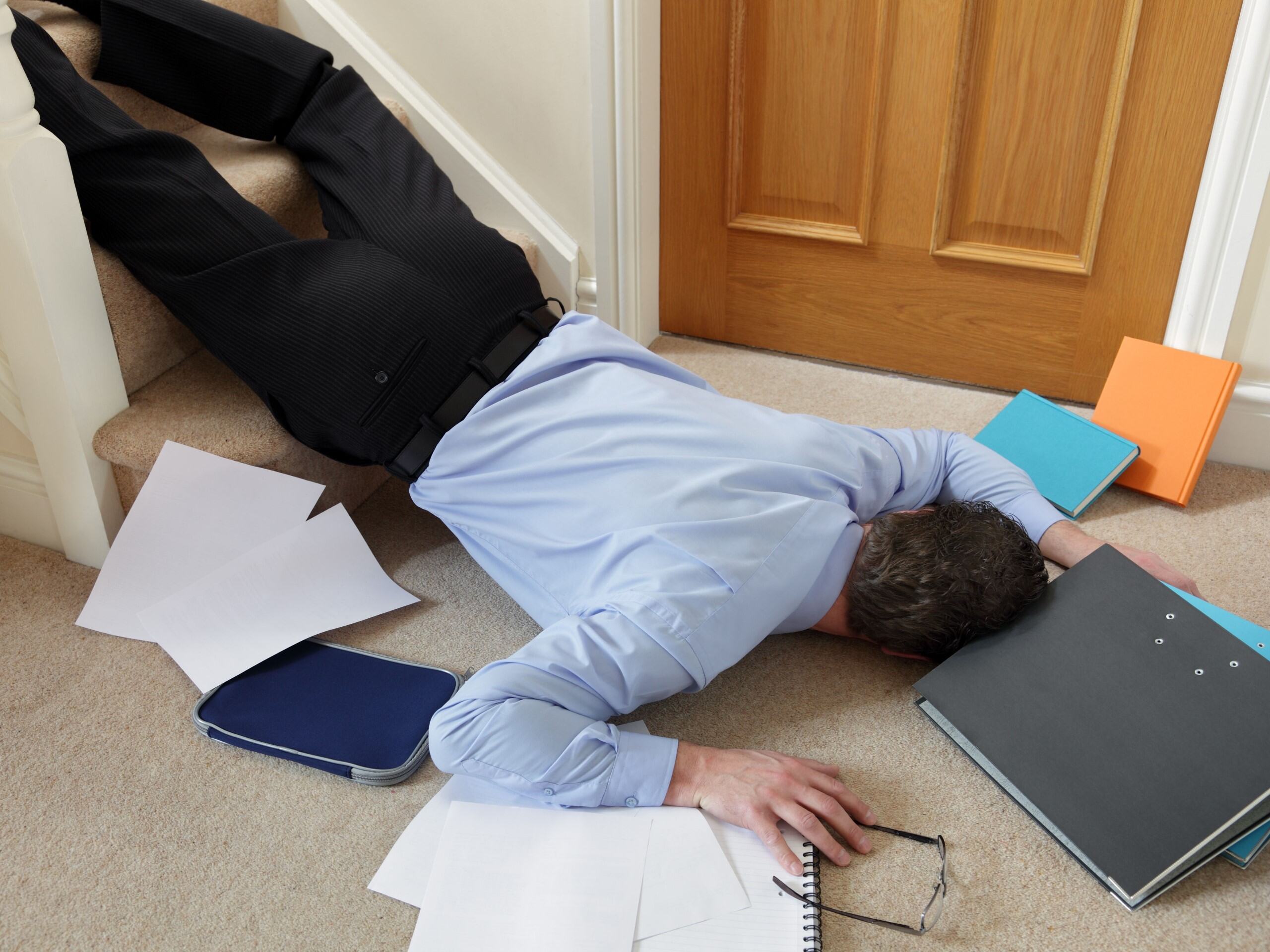 After tripping and falling down the stairs, a businessman lays in a heap of folders and papers