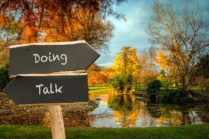 A sign that says "Doing" pointing one way and a sign that says "Talk" pointing the other way