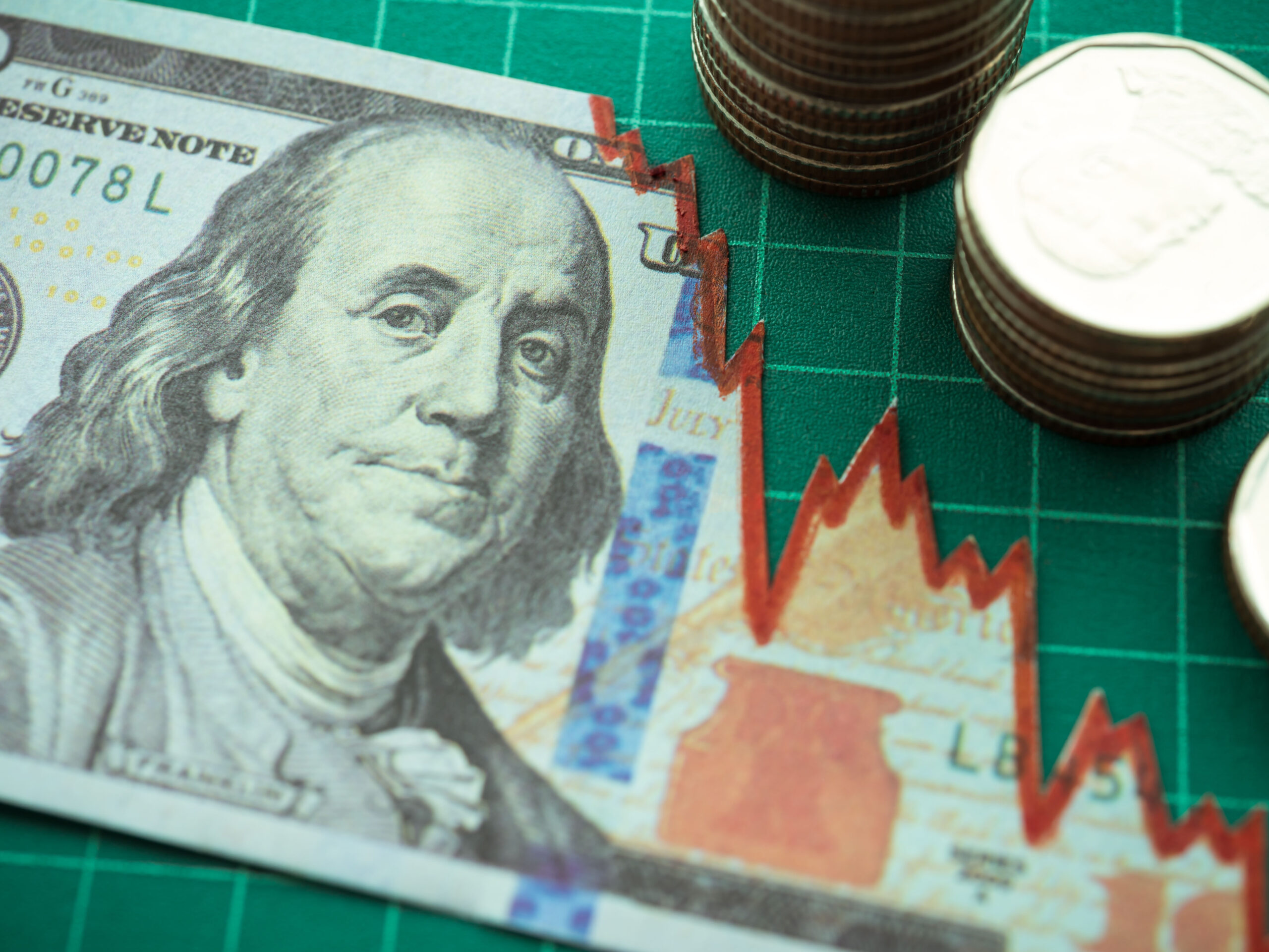 A U.S. $100 bill turned into a stagflation chart next to stacks of coins