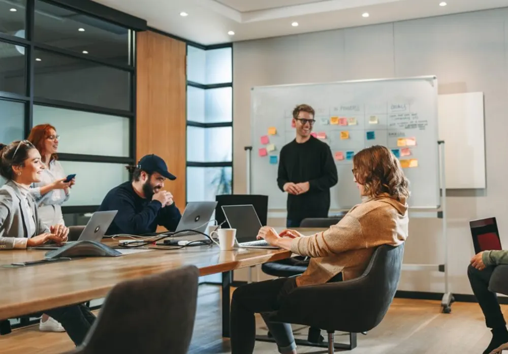 A corporate team works on a project in a meeting room, balancing competition and collaboration.